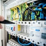 Elektryk reguluje kolorowe przewody w rozdzielnicy elektrycznej