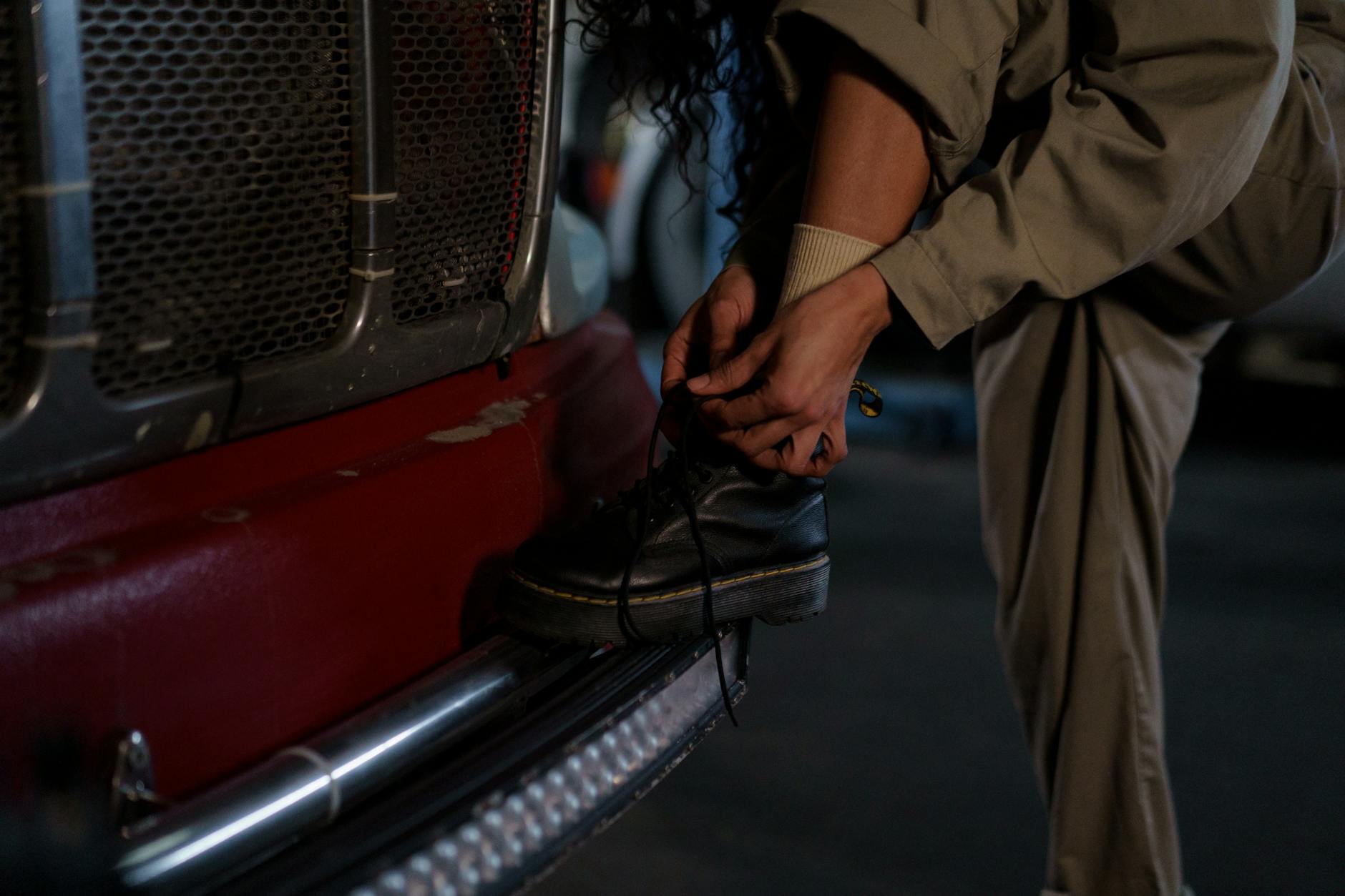 Kobieta w stroju biurowym sznurująca buty na zderzaku samochodu