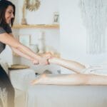 Ból śródstopia po całym dniu: jakie podeszwy i zapięcia pomagają? Masażysta wykonuje relaksujący masaż stopy w gabinecie spa