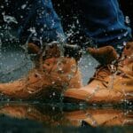 Męskie skórzane buty trekkingowe chlapiące wodę w kałuży