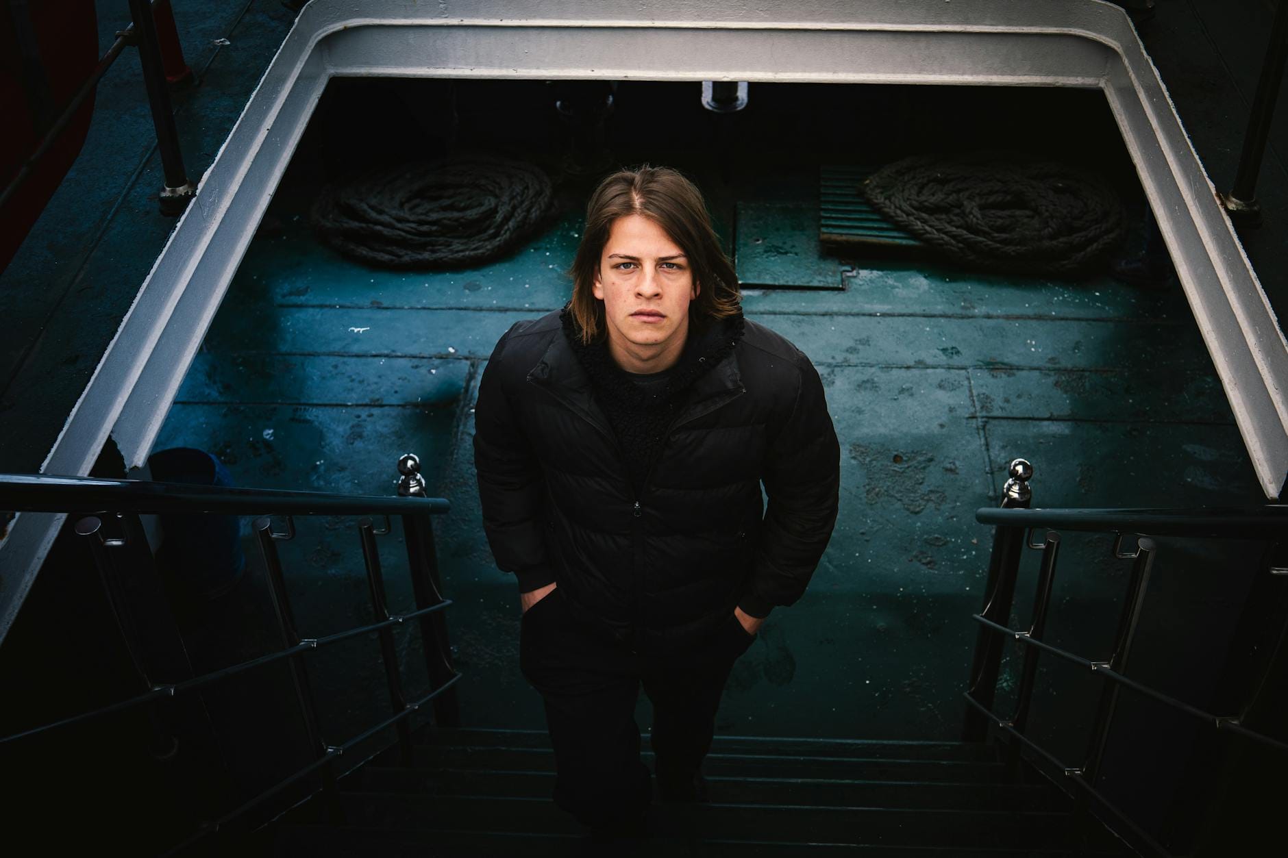 Mężczyzna w czarnej kurtce stoi na schodach w eleganckim zimowym stroju