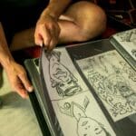 Osoba w szortach ogląda album komiksowy w sportowych sneakersach