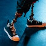 Protezy nóg z czarnymi butami sportowymi na niebieskiej posadzce
