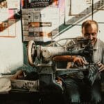 Szewc odnawia skórzane buty vintage przy starej maszynie w warsztacie