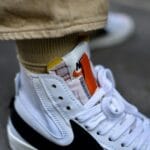 Białe sportowe sneakersy na betonowym chodniku, detal z bliska