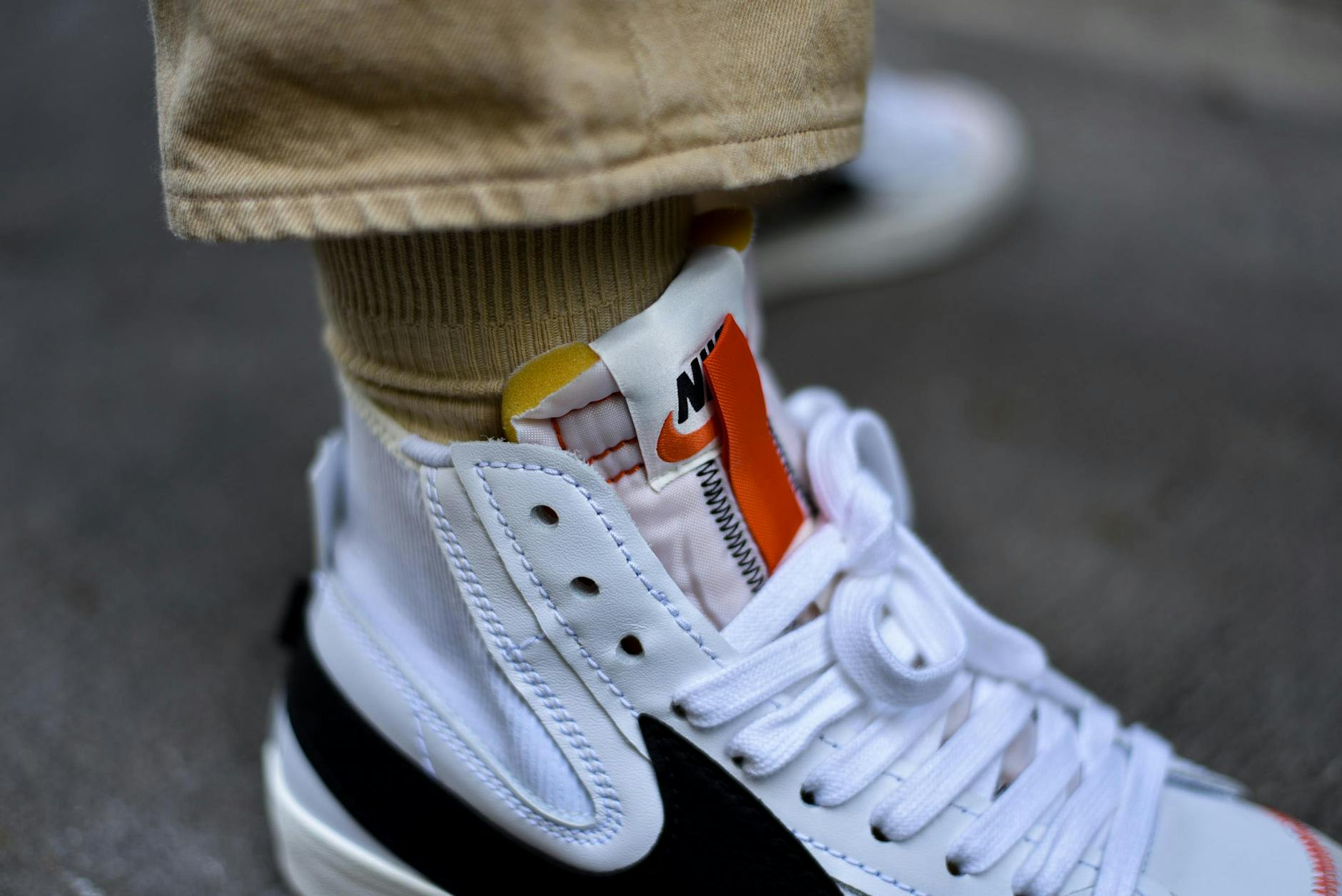 Białe sportowe sneakersy na betonowym chodniku, detal z bliska