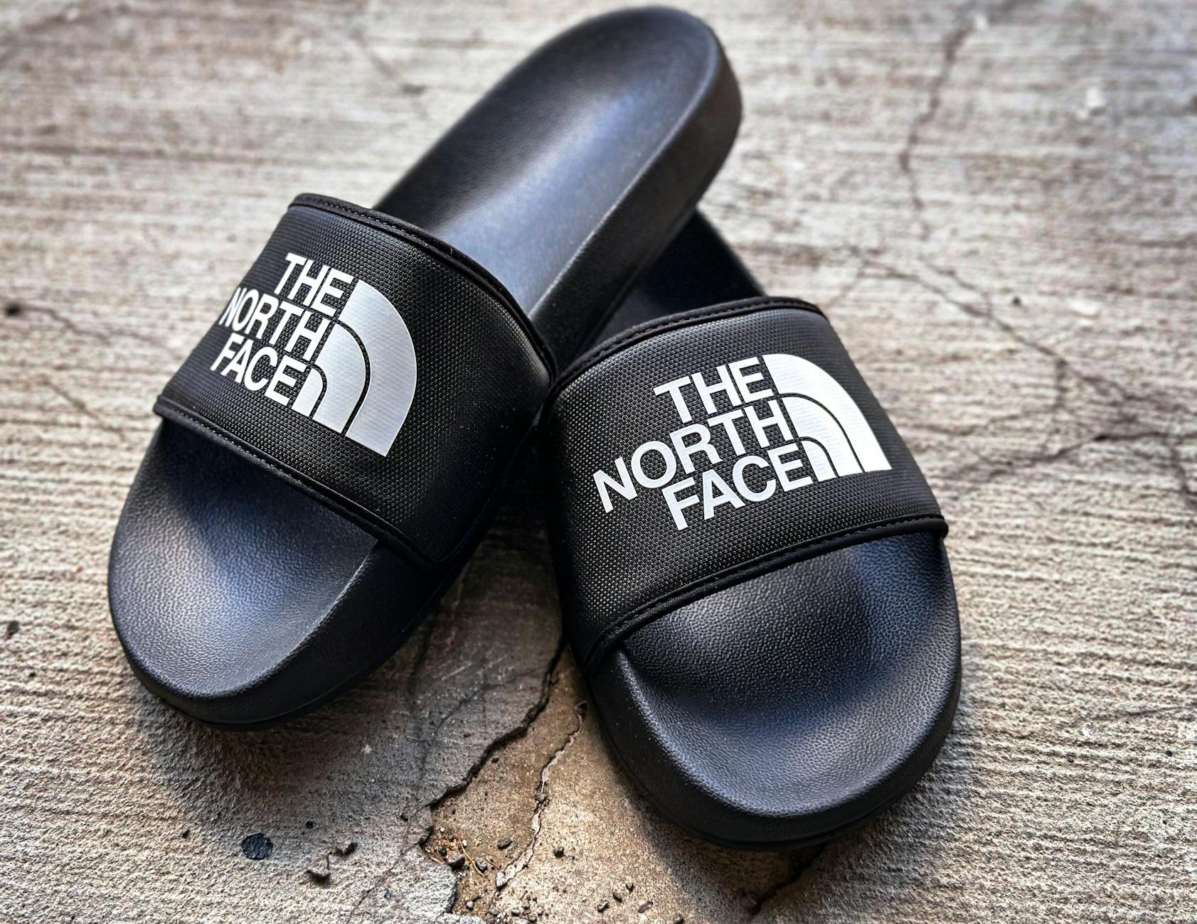 Czarne miejskie klapki na popękanym chodniku, eleganckie i casualowe