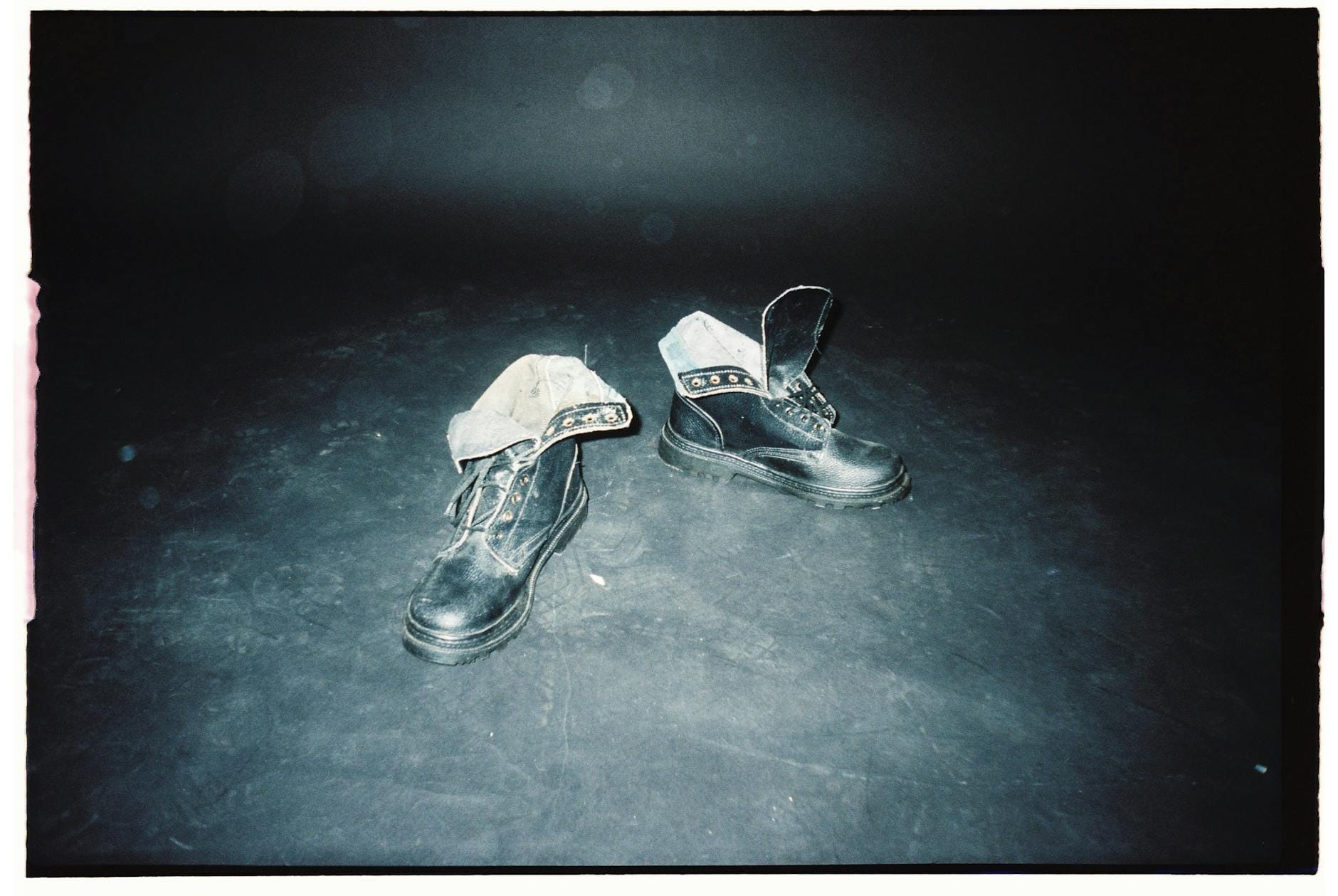 Czarne skórzane buty vintage w świetle na zakurzonej podłodze Czarne skórzane buty vintage w świetle na zakurzonej podłodze