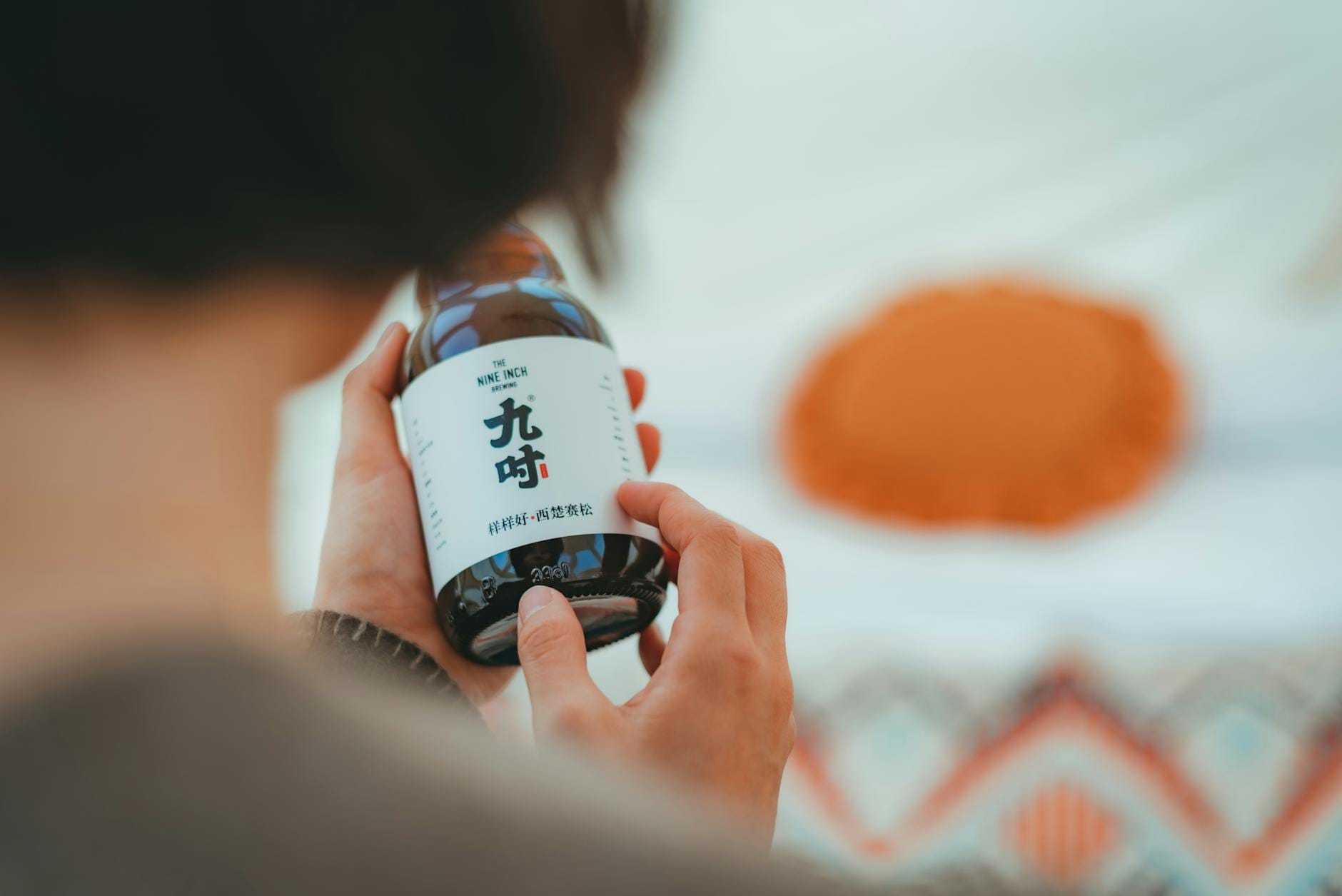 Dłoń trzymająca butelkę z etykietą w azjatyckiej kaligrafii