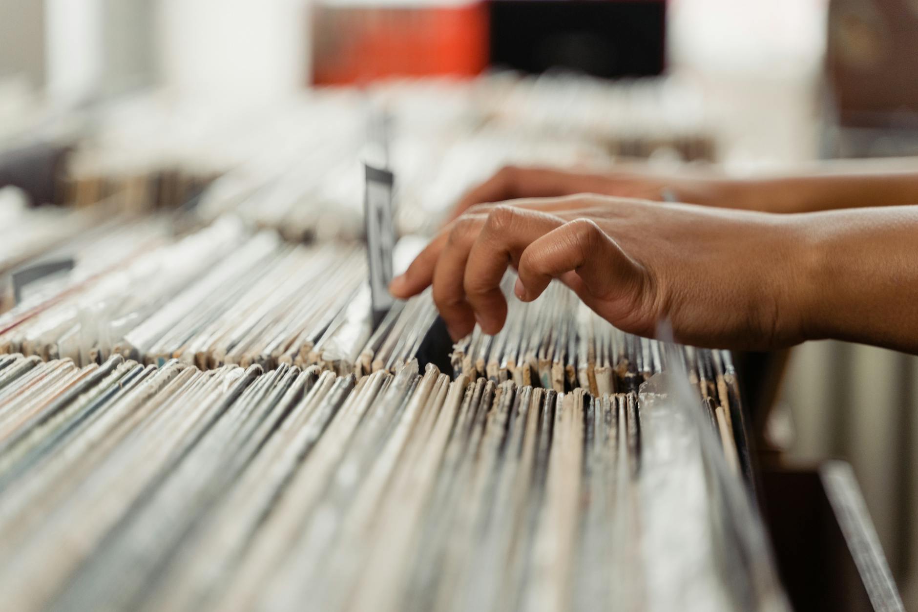 Dłonie przeglądające płyty winylowe w sklepie z muzyką