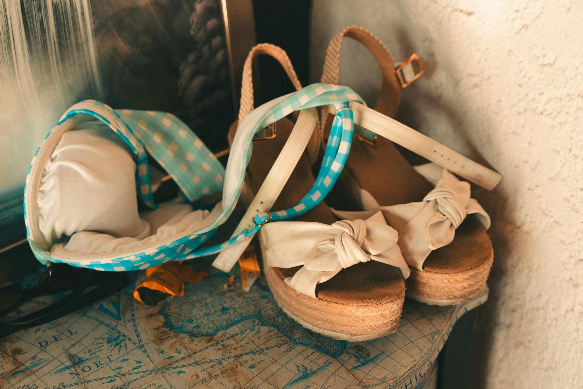 Letnie sandały i bikini w kratę ułożone na dekoracyjnej mapie