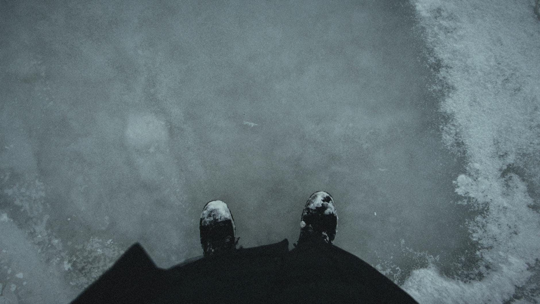 Męskie zimowe buty na ośnieżonym chodniku, widok z góry