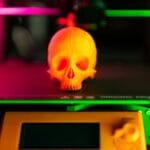 Pomarańczowa czaszka drukowana na drukarce 3D w kolorowym świetle