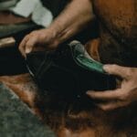 Ręczne szycie skórzanego buta przez szewca w warsztacie