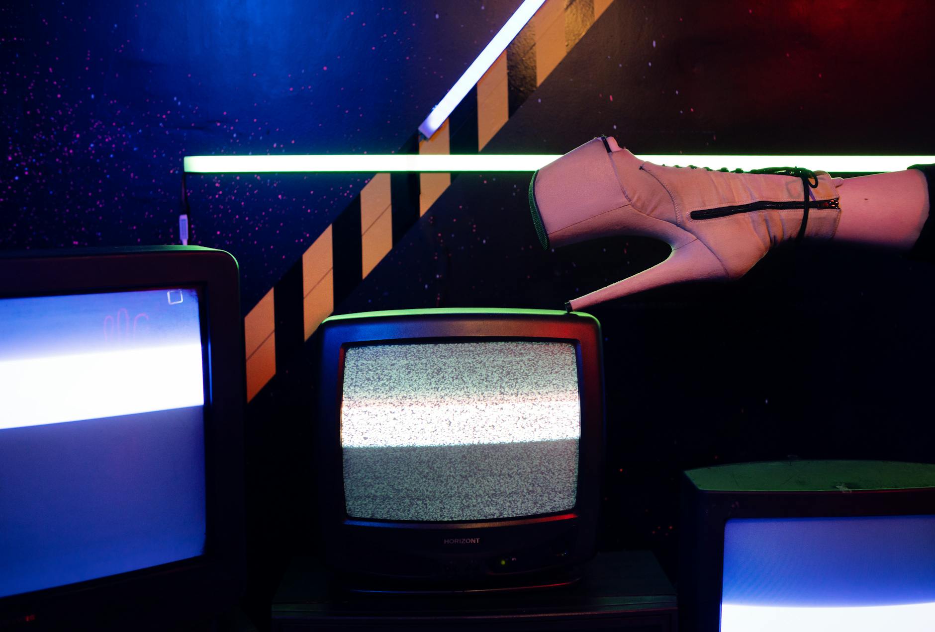 Różowy szpilka stojący na starym telewizorze w neonowym świetle