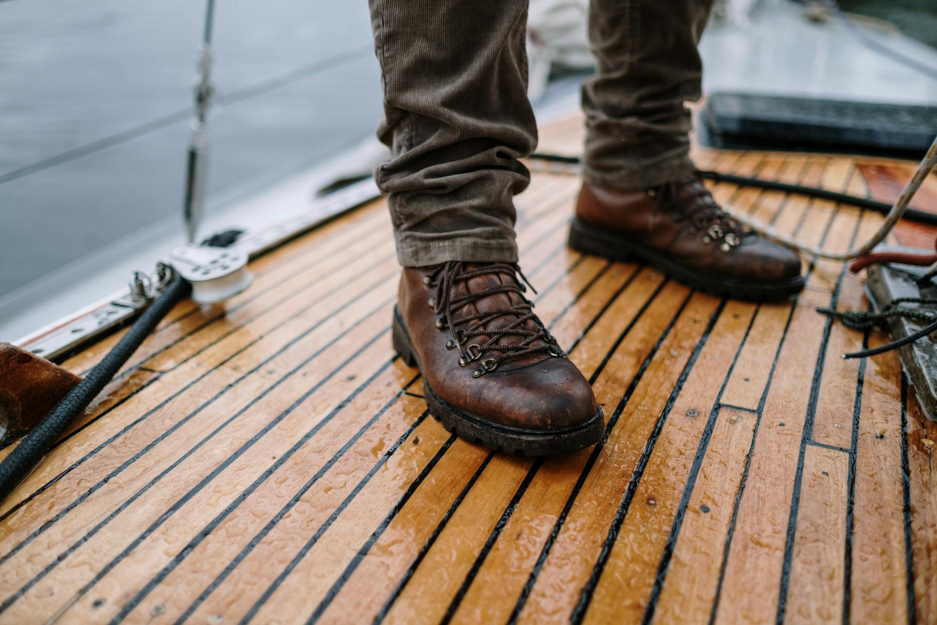 Skórzane górskie buty trekkingowe na mokrym drewnianym pokładzie łodzi