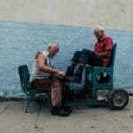 Starszy mężczyzna czyści skórzane buty drugiego na zewnątrz