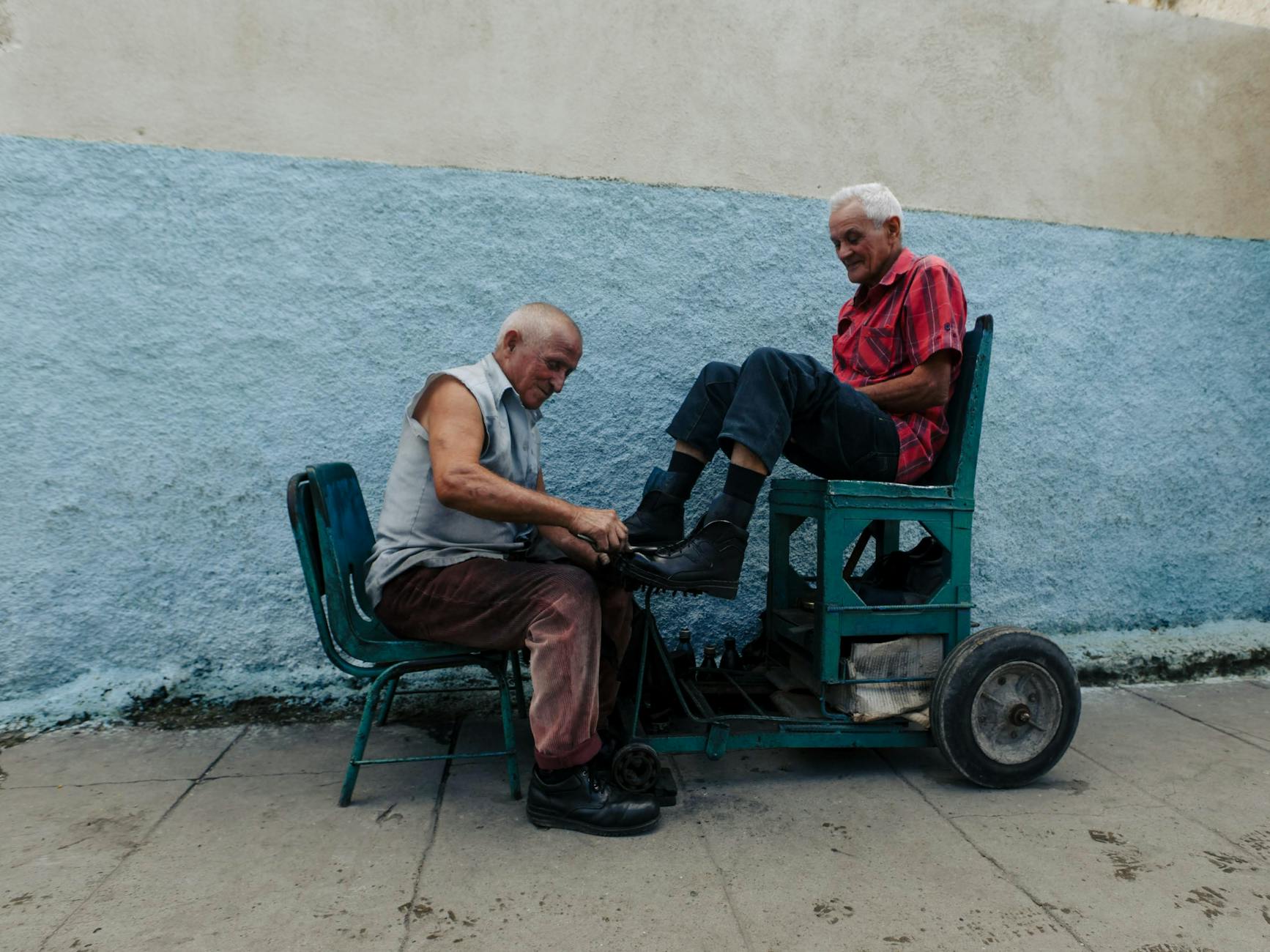 Starszy mężczyzna czyści skórzane buty drugiego na zewnątrz