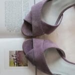 Zamszowe sandały na obcasie leżące na otwartej książce z tekstem