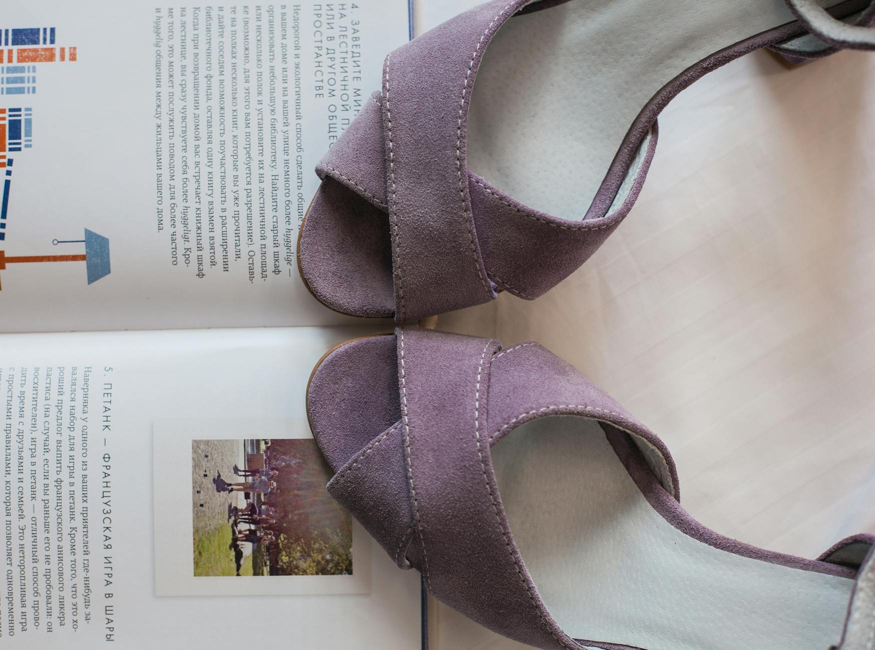 Zamszowe sandały na obcasie leżące na otwartej książce z tekstem