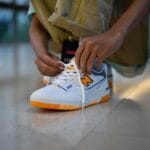 Zbliżenie na osobę sznurującą kolorowe sneakersy w pomieszczeniu