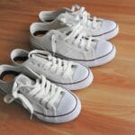 Białe sneakersy na drewnianej podłodze, gotowe do prostych poprawek DIY
