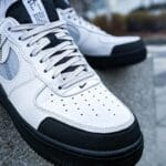 Białe i czarne modne sneakersy na miejskim tle