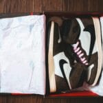 Nowe uniwersalne sneakersy w pudełku kartonowym na drewnianej podłodze