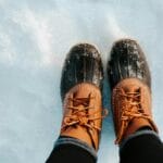 Zbliżenie zimowych butów trekkingowych stojących na świeżym śniegu