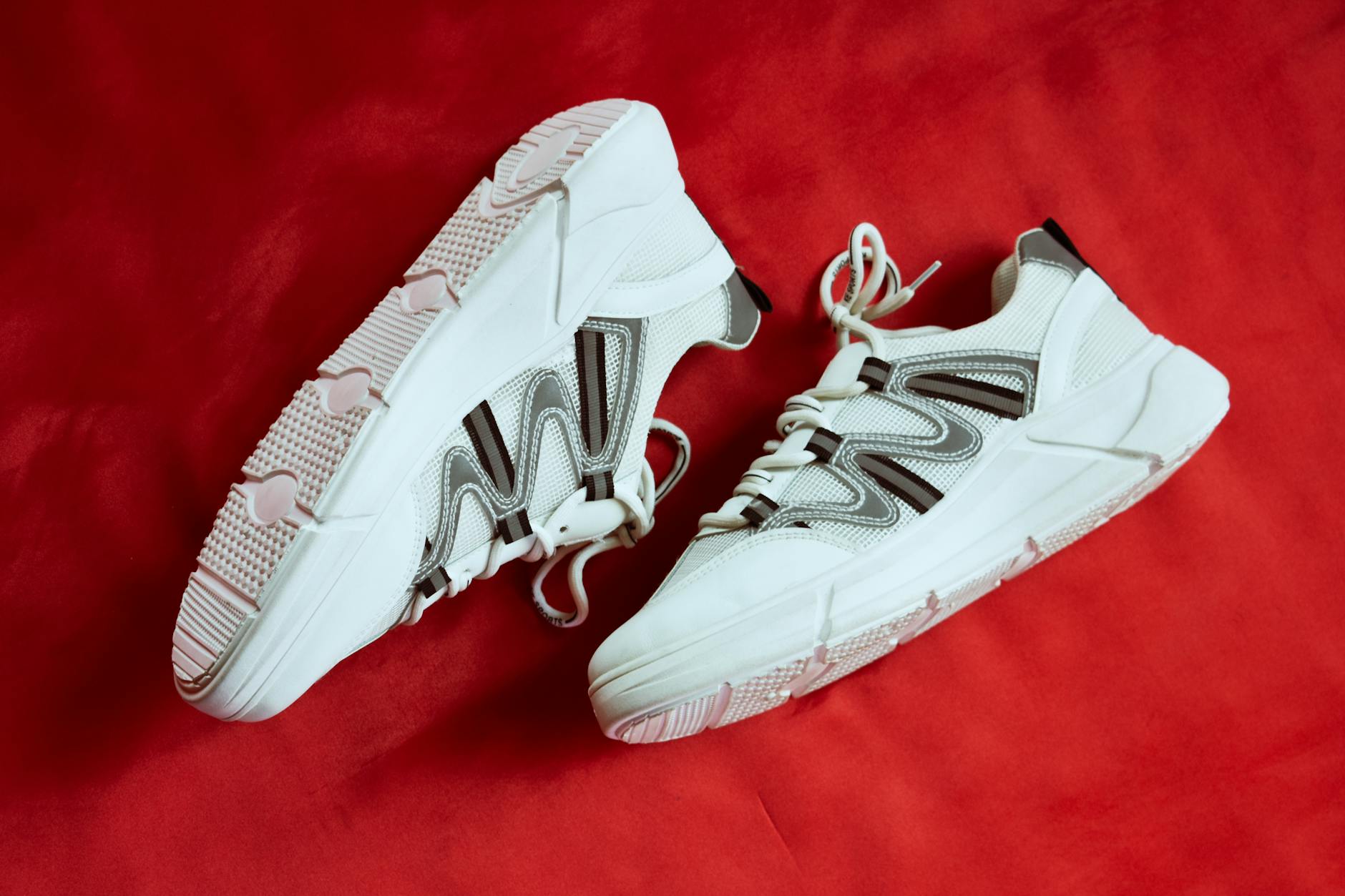 Białe designerskie sneakersy na intensywnie czerwonym tle