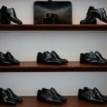 Czarne skórzane buty luksusowe i akcesoria na drewnianych półkach sklepu