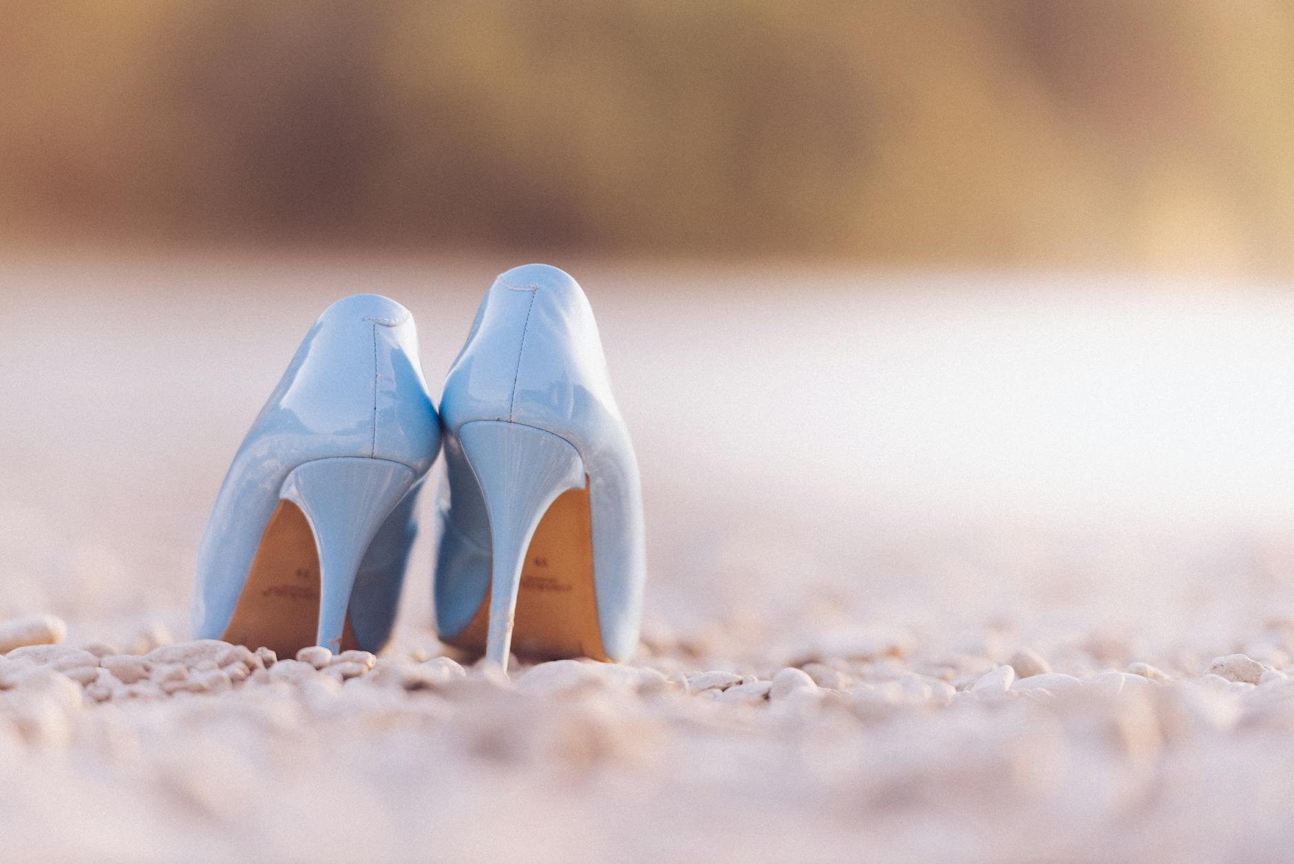 Niebieskie szpilki stojące na kamienistej plaży nad wodą