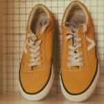 Żółte sneakersy z białymi sznurówkami na półce jako przykład designu