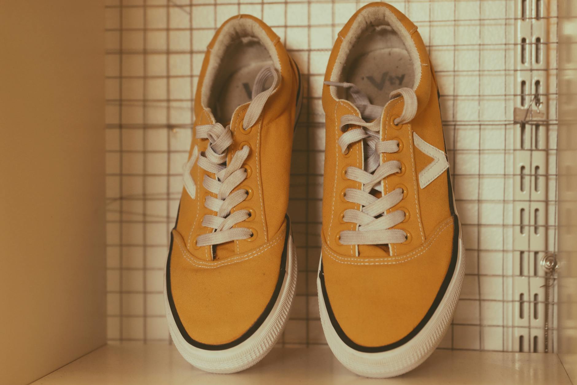 Żółte sneakersy z białymi sznurówkami na półce jako przykład designu