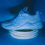 Biały futurystyczny sneaker na podświetlonym stojaku w niebieskim świetle