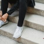 Mężczyzna wiążący sportowe buty na schodach na zewnątrz