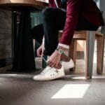 Elegancki mężczyzna w bordowej marynarce wiąże sznurowadła butów