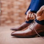 Mężczyzna wiąże sznurowadła brązowych eleganckich butów skórzanych