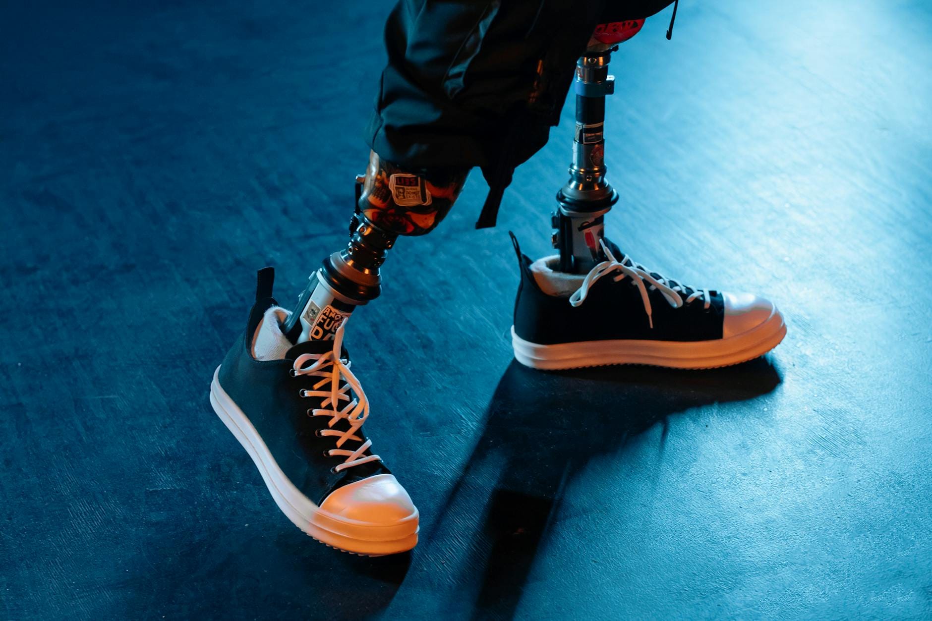 Protezy nóg z czarnymi sneakersami na niebieskiej posadzce