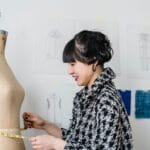 Projektantka mierzy centymetr krawiecki na manekinie w pracowni